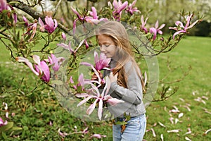 A little girl smelling a pink magnolia