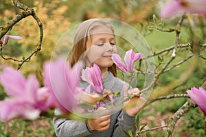 A little girl smelling a pink magnolia