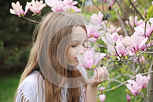 little girl smelling pink magnolia