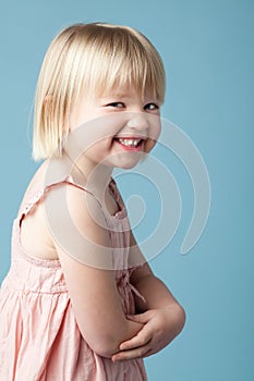 Little girl, smile and playful in studio with portrait for child development on blue background. Sneaky, rascal and photo
