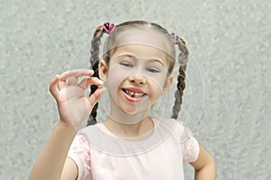 Little girl smiles and holds a lost milk tooth in her hands, selective focus, pastel colors