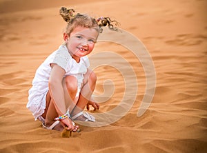 Little girl smiles and plays sand