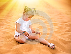 Little girl smiles and plays sand