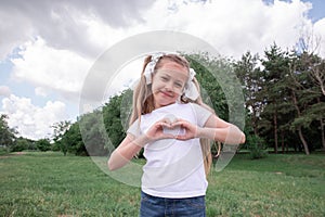 A little girl smiles and shows a heart sign with her hands. child and love