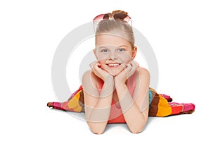 Little girl smiling in colorful skirt is lying. Happy child with hands near face, isolated on white background