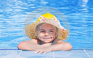 Little girl smiling on the edge of the swimming pool