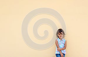 Little girl smiling and possing next to a yellow wall