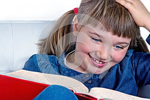 Little girl smiling and reading a book