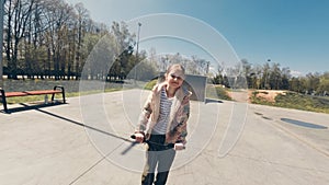 little girl smiling and riding by a Kick Scooter and extreme Park