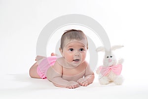 Little girl smiling with a toy rabbit lies on white background.