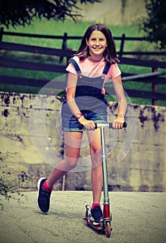 Little girl smiling white plays with scooter with old toned effe