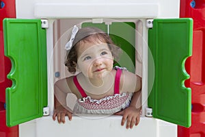 Little girl smiling through the window of kids playhouse