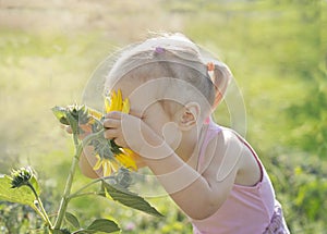 Little girl sniffing a sunflower