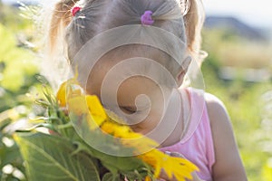 Little girl sniffing a sunflower