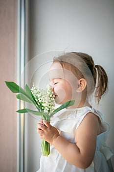 Little girl sniffs lilies of the valley