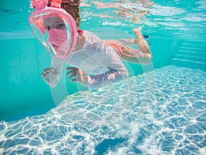 Little girl snorkeling underwater in the pool. Learning child to swim and diving