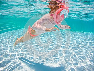 Little girl snorkeling underwater in the pool. Learning child to swim and diving