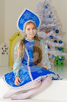 Little girl Snow Maiden near the New Year tree.