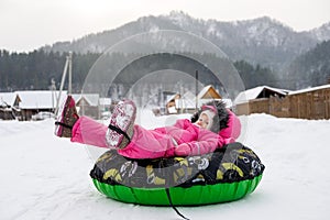 Little girl in snow tube. Winter tubing. Winter leisure activity concept. Family winter fun