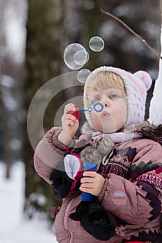 Little girl with soap bubles in winter