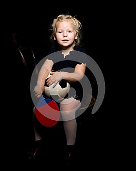 Little girl with a soccer ball on a black background.
