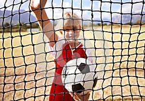 Little girl, soccer player and ball on goal net, smile and happy for game, field and child. Outdoor, playful or sport