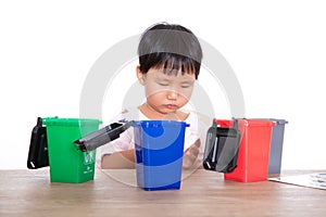 Little girl sorting garbage bin toys on playing table in front of white background