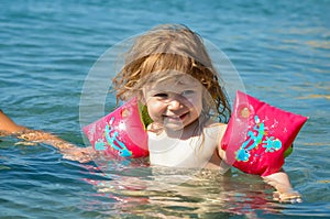 Little girl splashing in the crystal clear water in a lagoon
