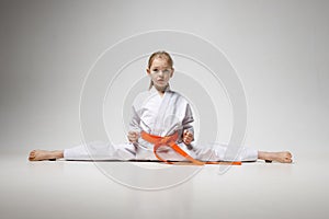 Little girl in a split pose on a white background, child karate fighter