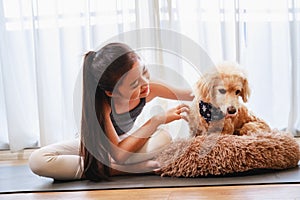 Little Girl in sportswear playing with her dog on a yoga mat in the living room at home. New normal concept