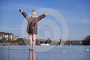 Little girl spread her arms to the sides, closed her eyes and turned her face to the rays of the sun