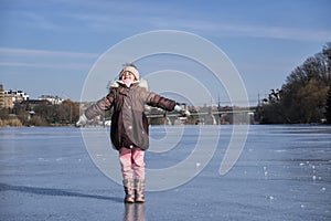 Little girl spread her arms to the sides, closed her eyes and turned her face to the rays of the sun