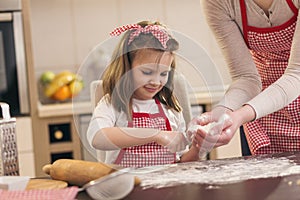 Little girl sprinkling flour over the kitchen table