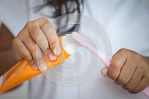 Little girl squeezes the toothpaste on the toothbrush