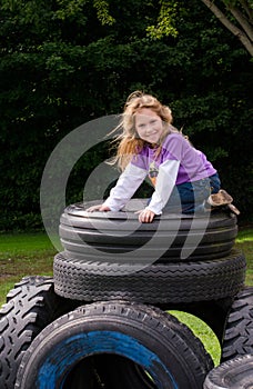 Little girl on stack of recycled tires