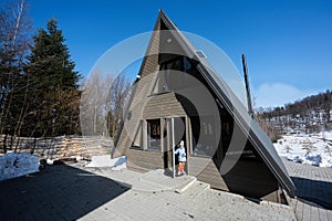 Little girl stand in door of triangle country tiny cabin house in mountains