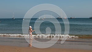 A little girl standing on at the adge of a sea and looking at the water photo