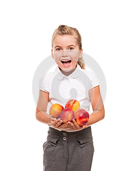 little girl standing against white backdrop with few fresh nectarines and smiling