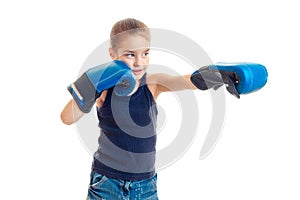 Little girl standing in front of the camera in boxing gloves and looks toward