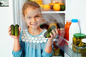 Little girl standing in front of a fridge and choosing food