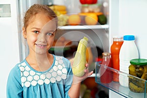 Little girl standing in front of a fridge and choosing food