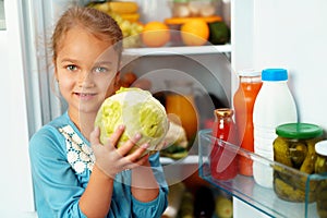 Little girl standing in front of a fridge and choosing food