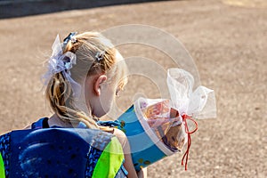 Little girl standing in front of the school building holding her candy cone