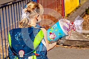 Little girl standing in front of the school building holding her candy cone