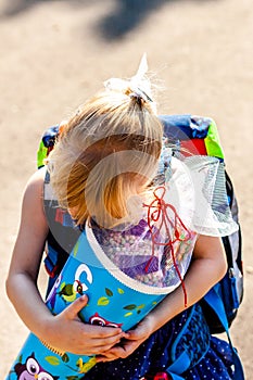 Little girl standing in front of the school building holding her candy cone