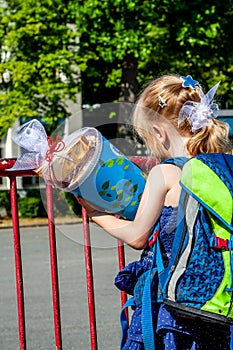 Little girl standing in front of the school building holding her candy cone