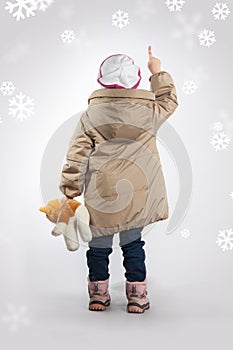 A little girl standing with his back pointing her finger.