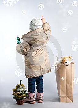 A little girl standing with his back pointing her finger.