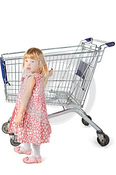 Little girl is standing near shopping basket