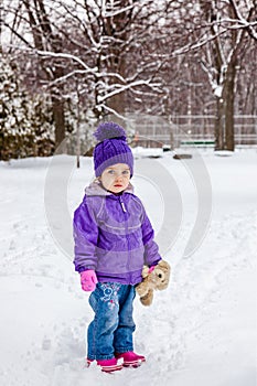 Little girl standing outside in snow. Winter cold weather.